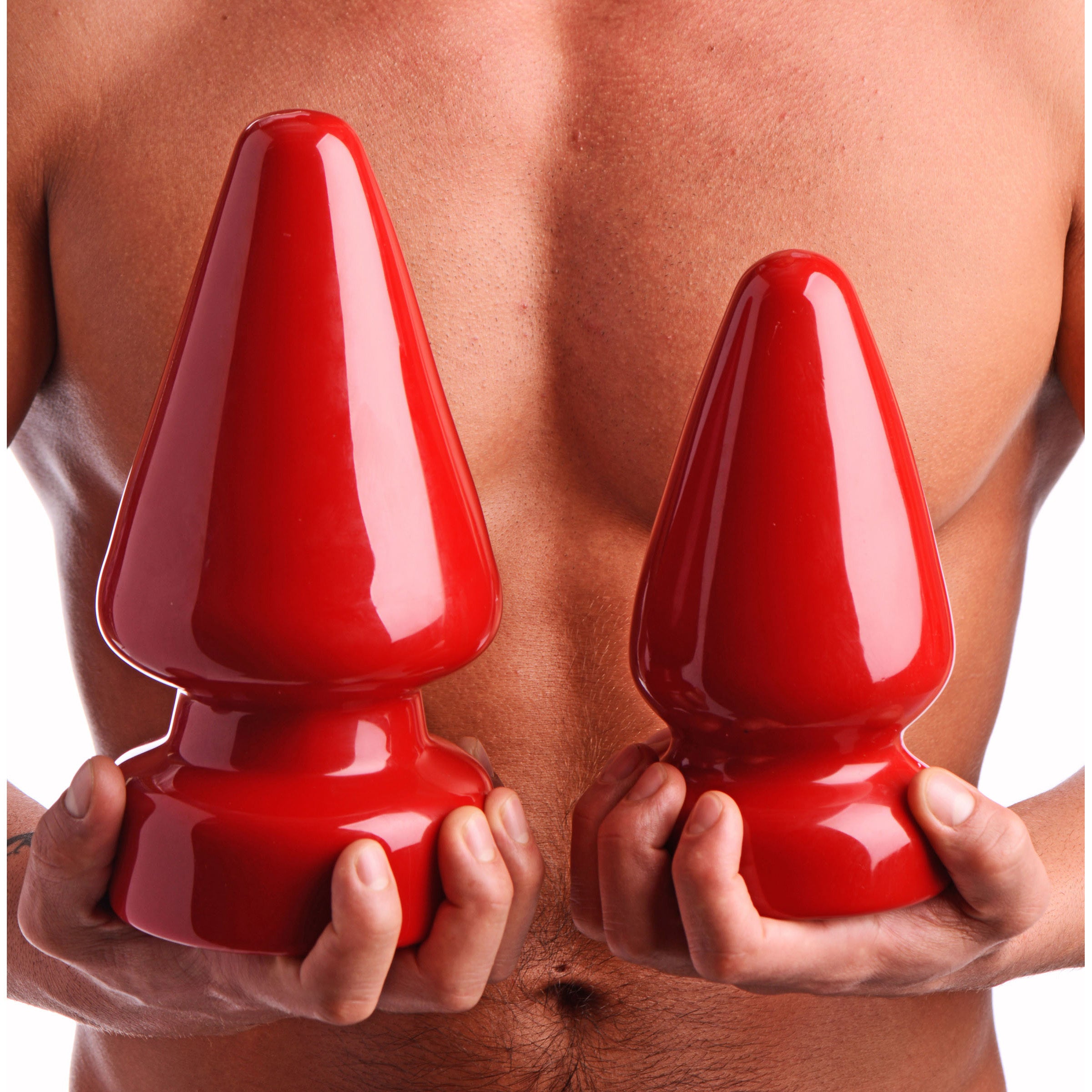 An individual displaying two sizes of red adult anal plugs