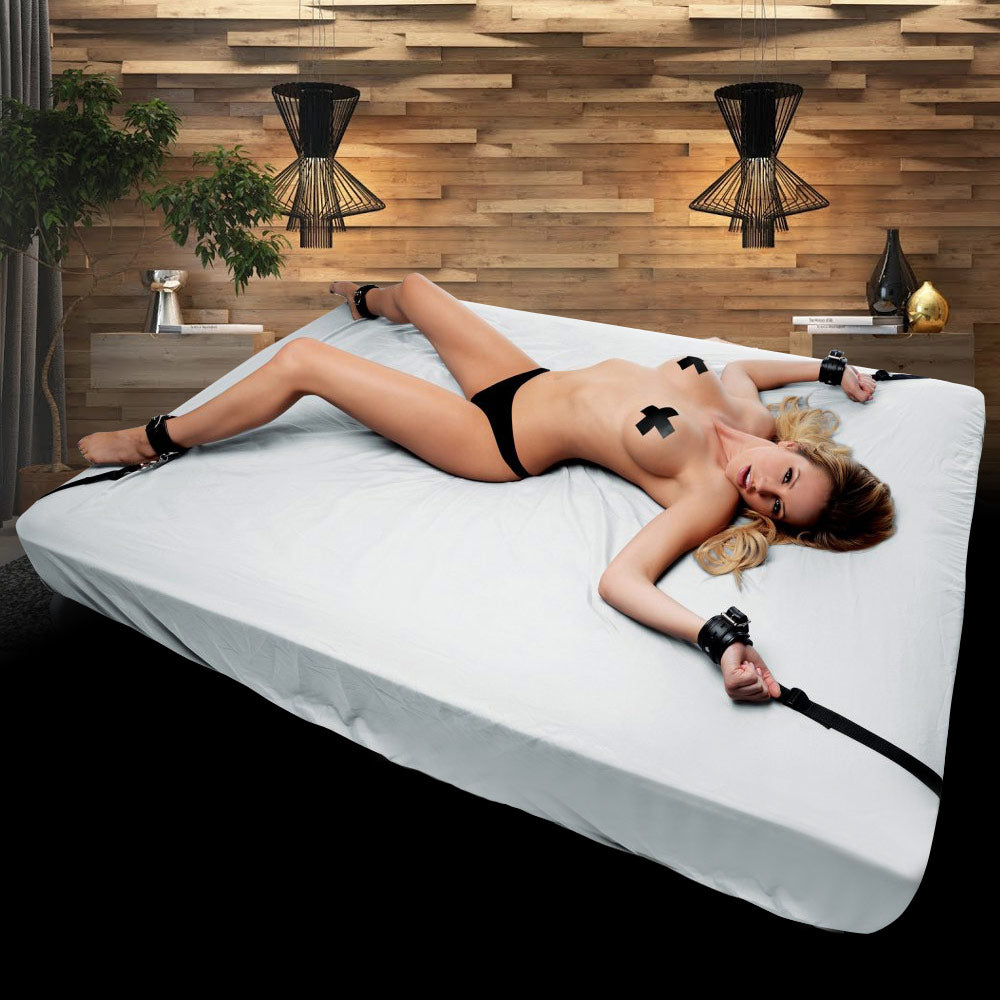 Deluxe Bed Restraint Kit with various bondage accessories displayed on a bed