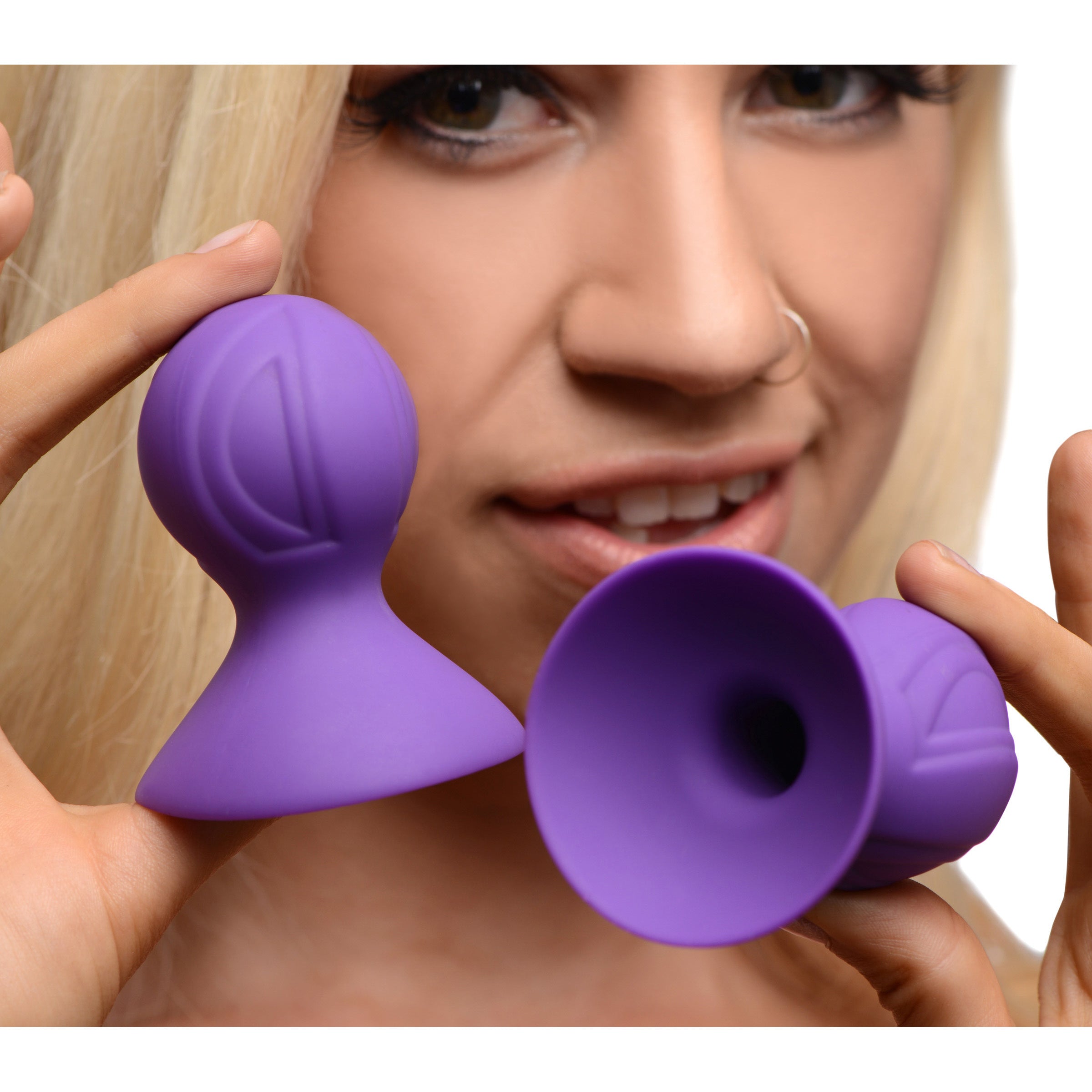 Person holding a pair of violet silicone nipple suckers