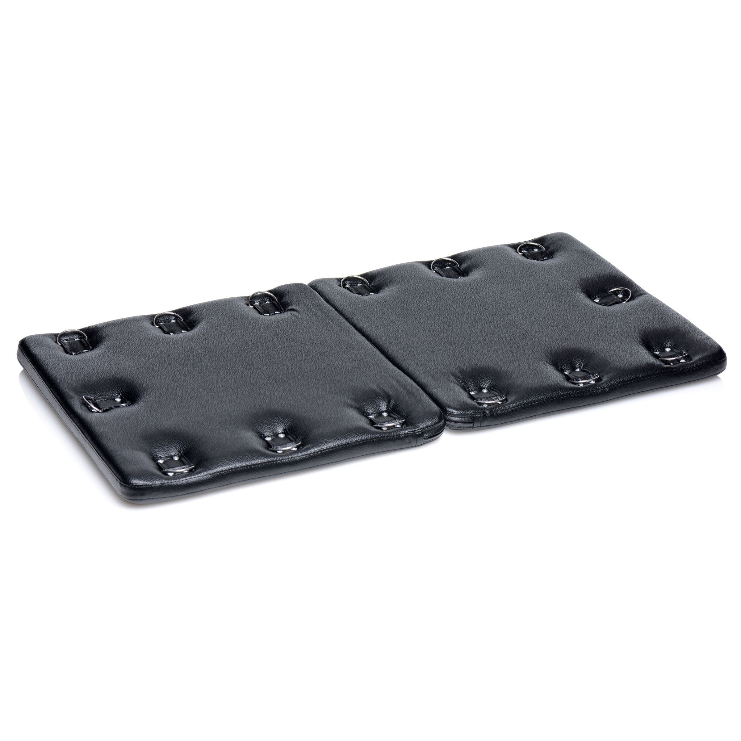 A black leather bondage board with restraint holes at each corner