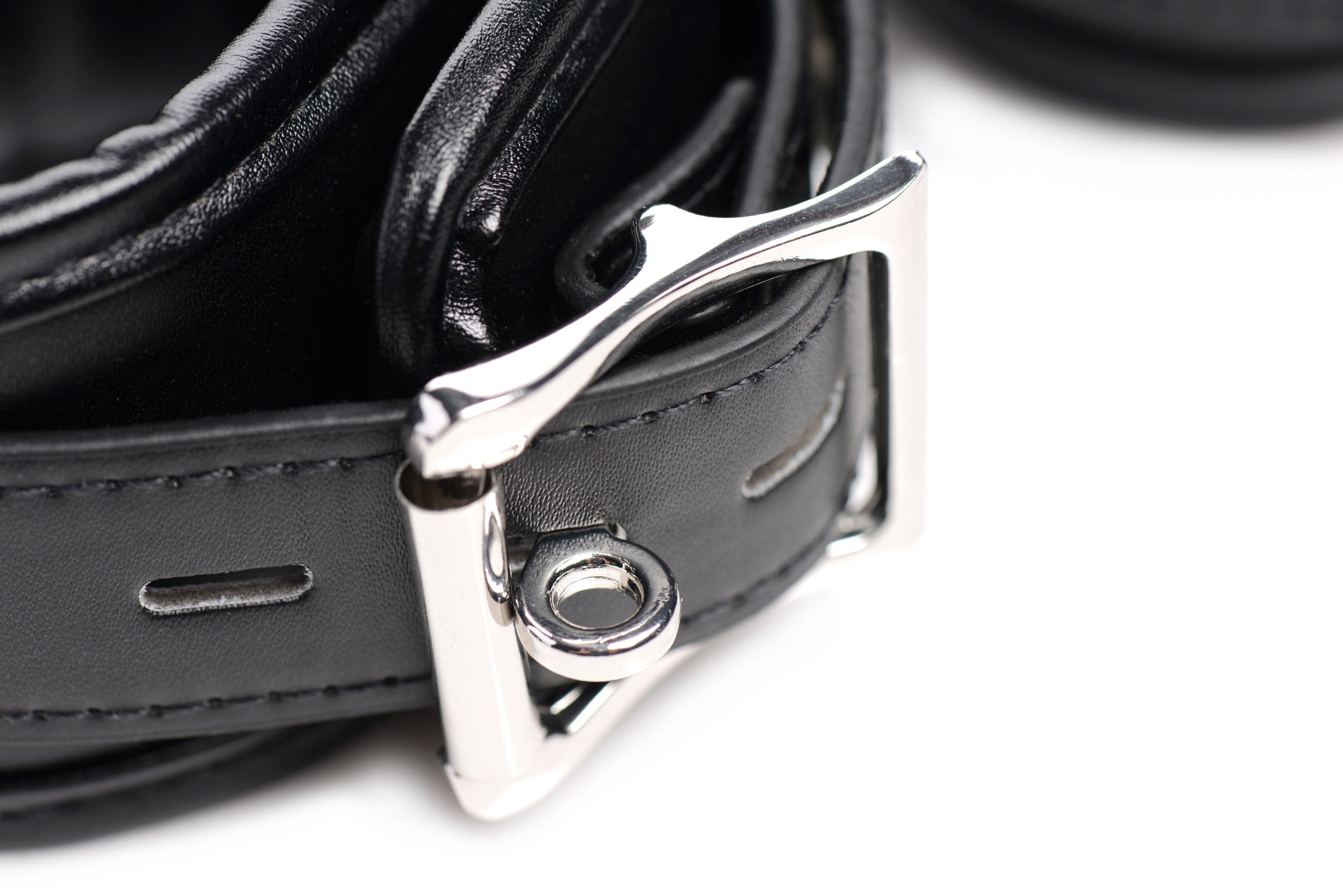 Close-up view of a black leather shackle set with metal buckles for bondage play