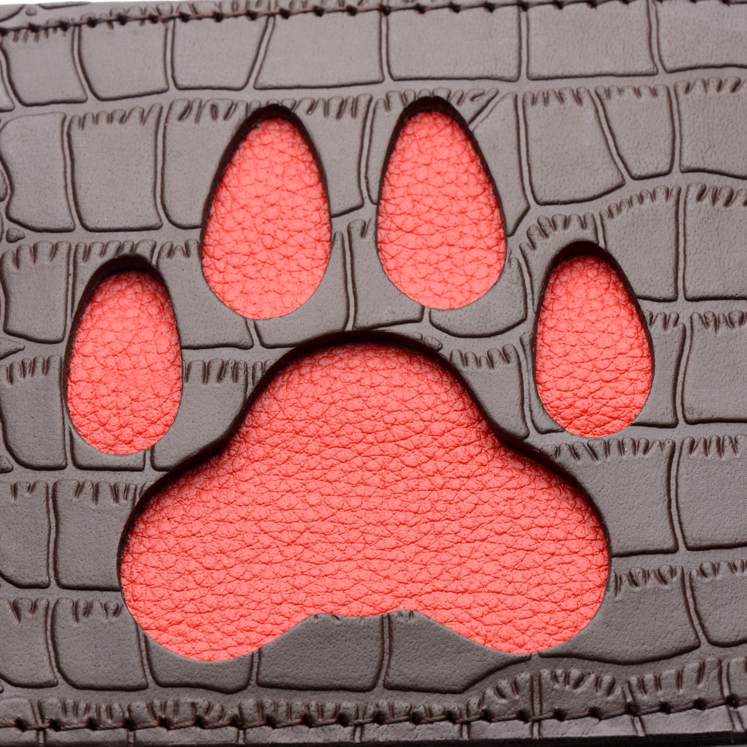 The backside of a puppy paw design leather paddle with a wrist strap