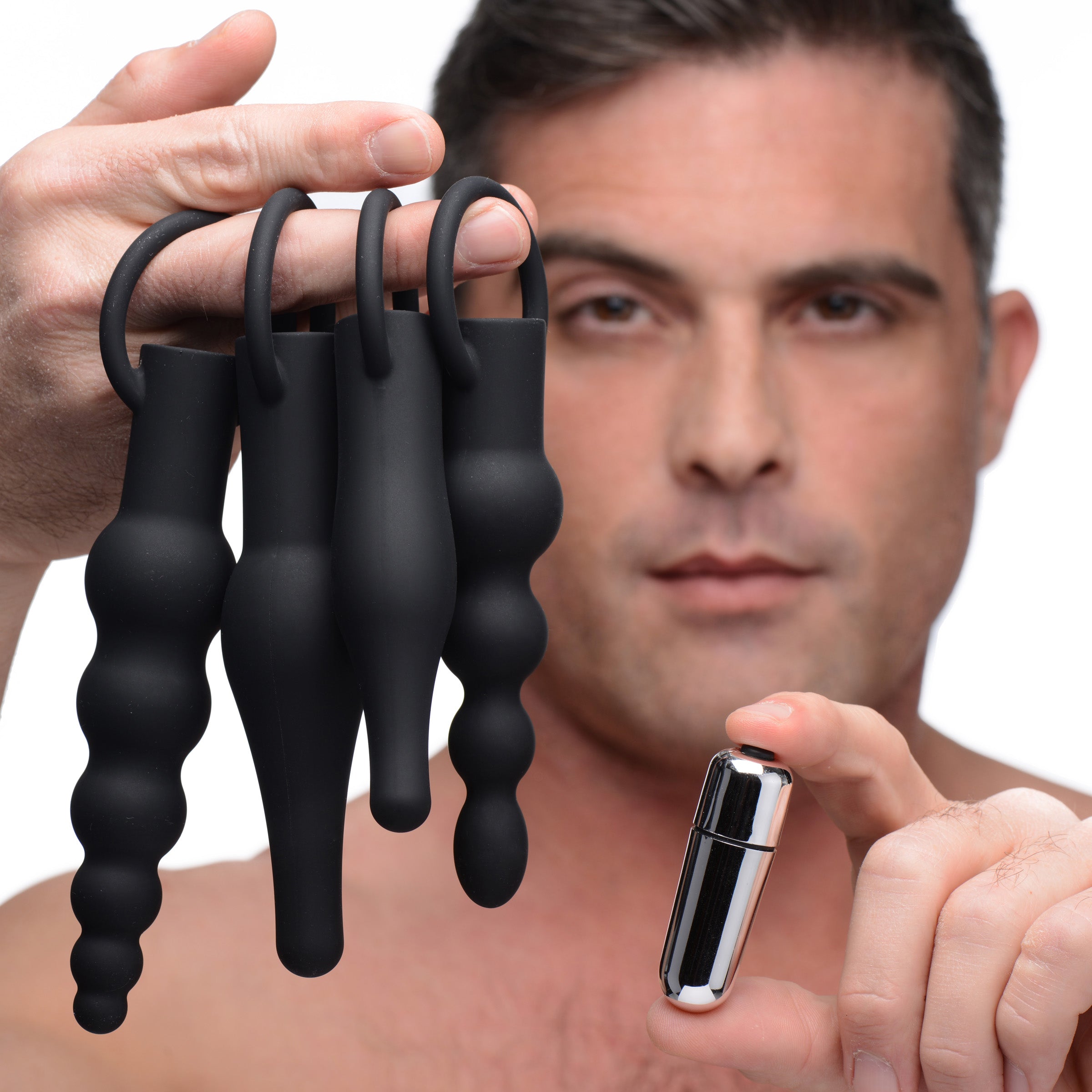 Individual holding a trio of black silicone plugs for progressive anal training