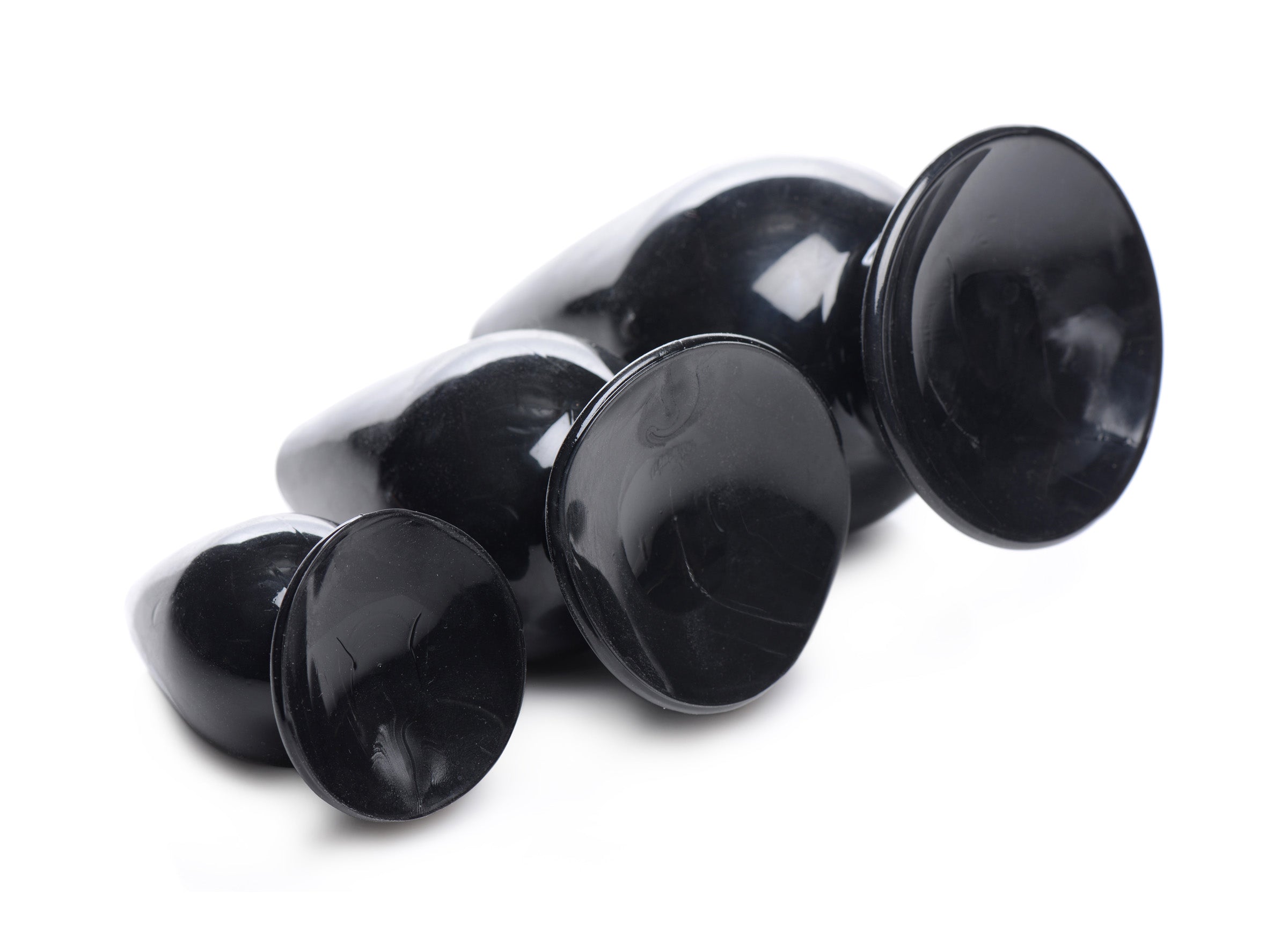 Trio of black Triple Cones anal plugs arranged on a white surface