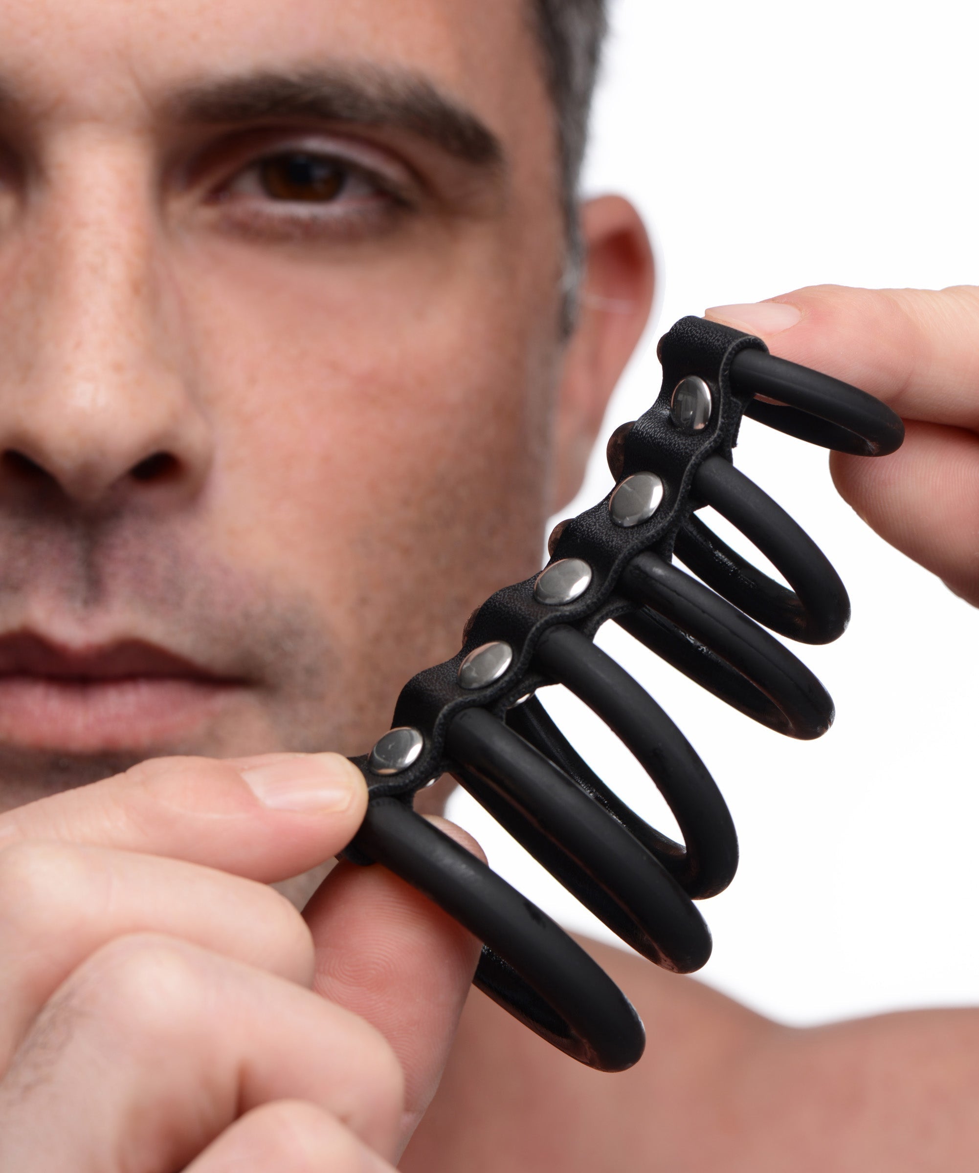 Person holding a black silicone chastity device with six rings