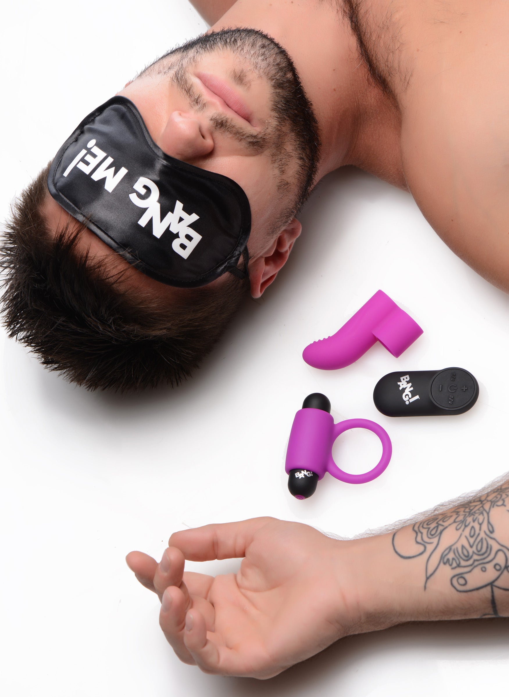 A man reclining with a purple and pink blindfold from the Couples Vibe Kit