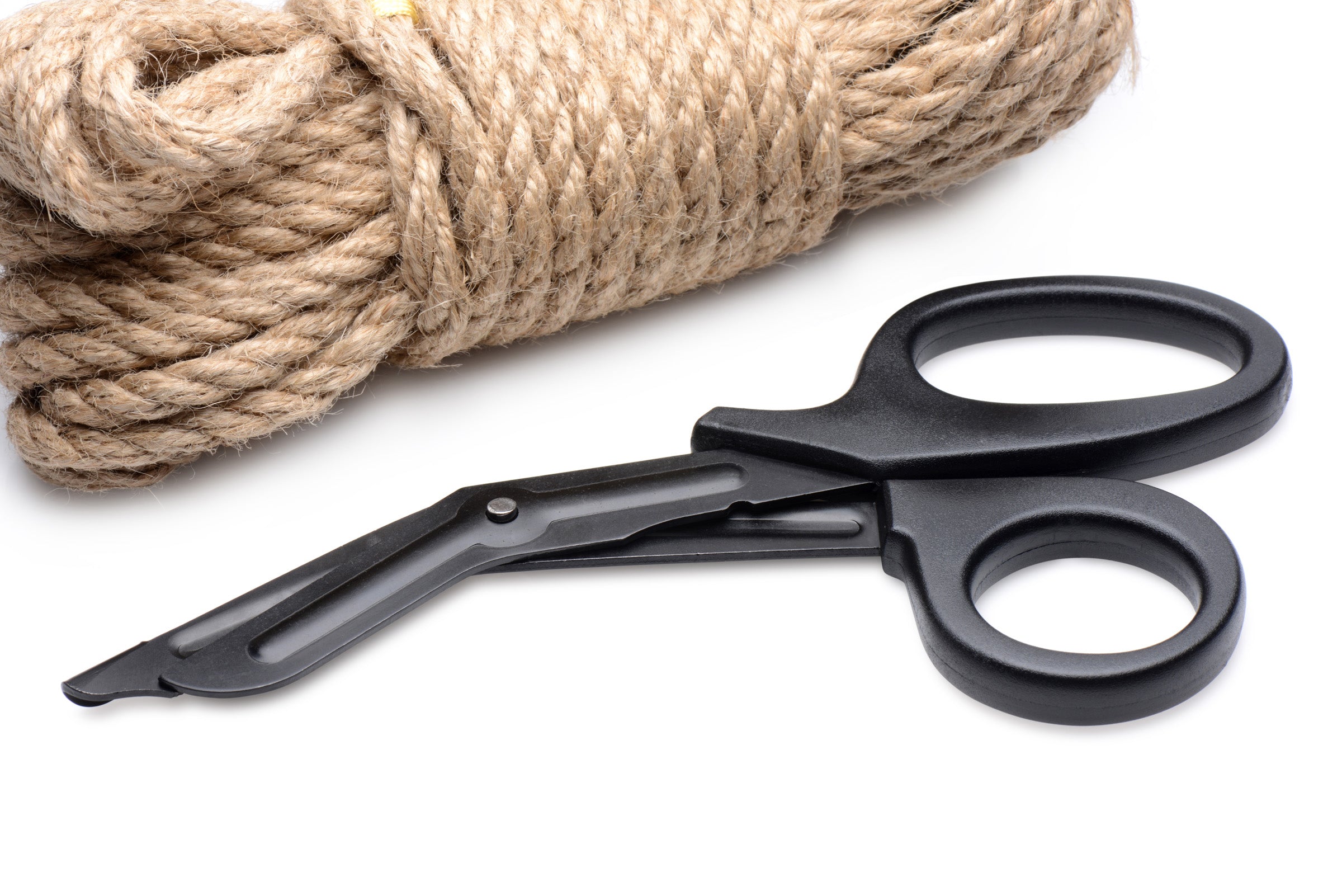 Bondage safety scissors lying next to a coil of rope on a white surface