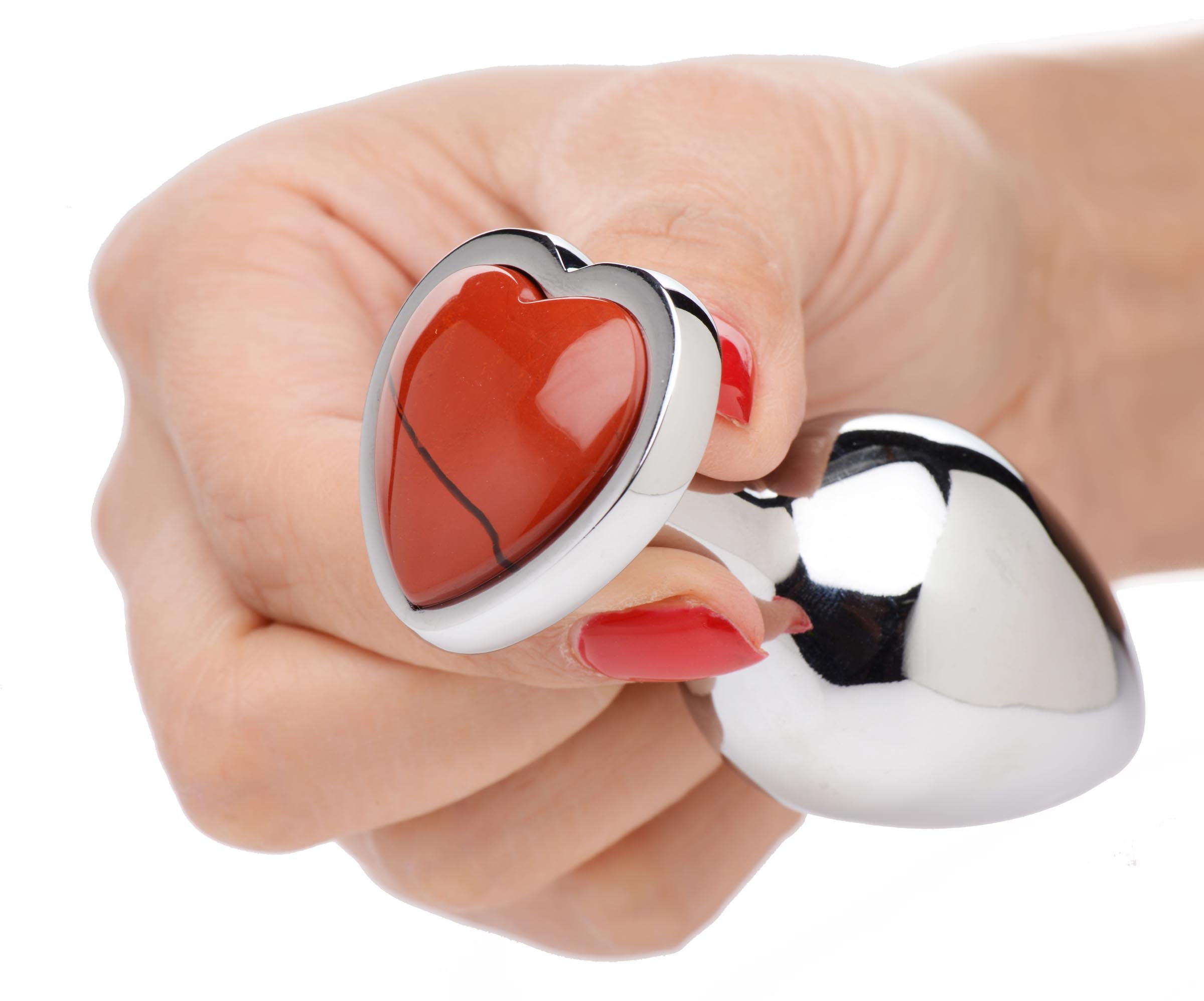 Hand holding a red Jasper heart anal plug with a reflective metal base