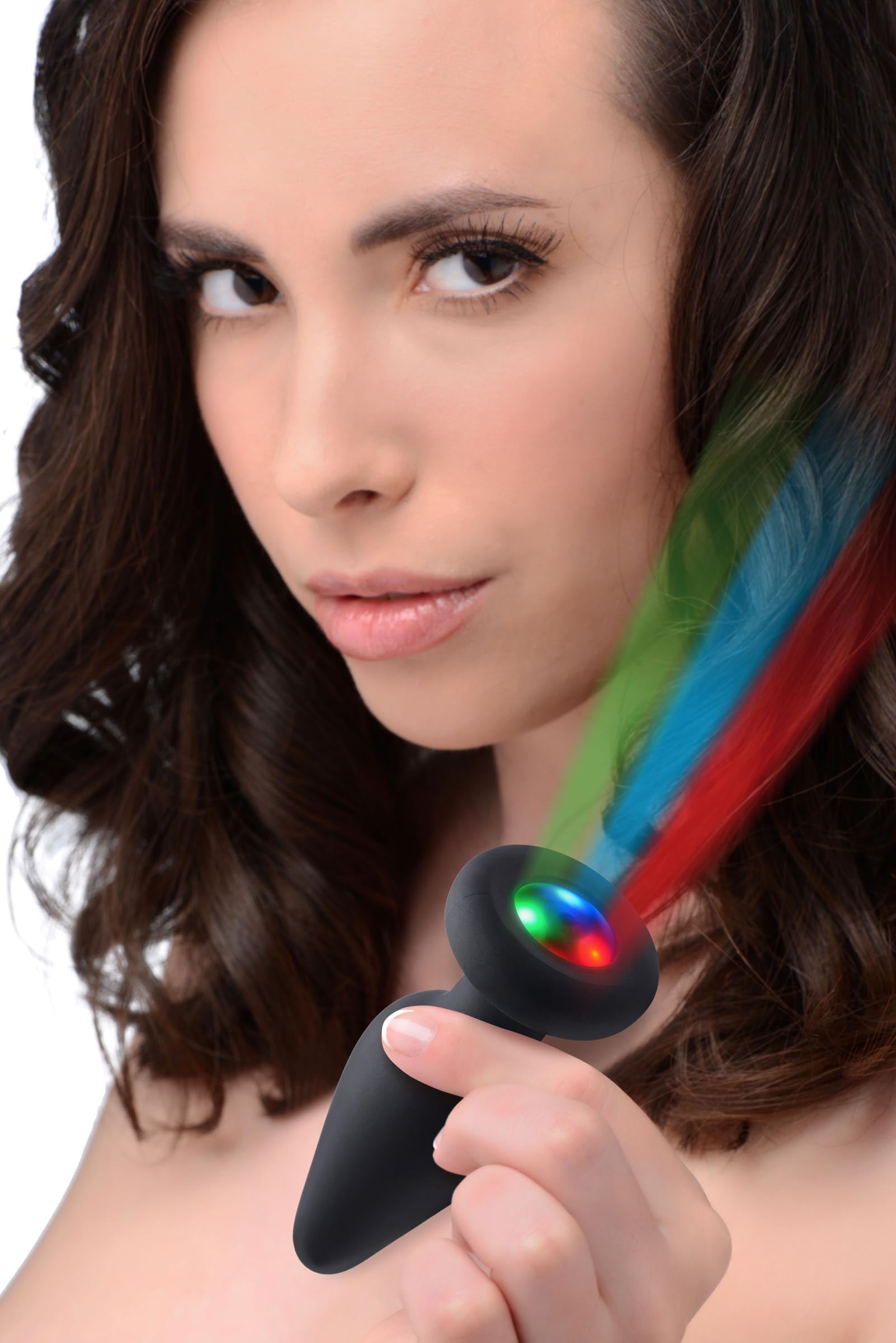 A person demonstrating how the silicone anal plug lights up with rainbow colors