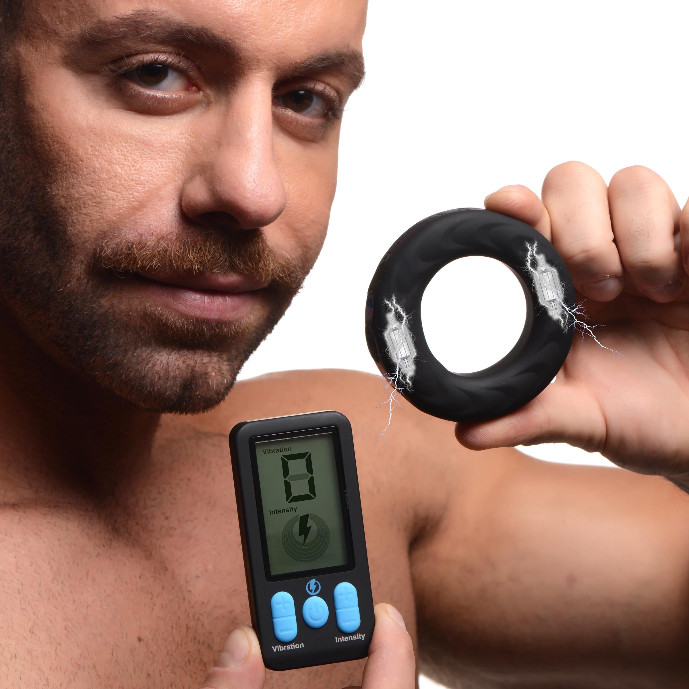 Person holding a wireless remote control next to an E-stim Pro silicone vibrating cock ring