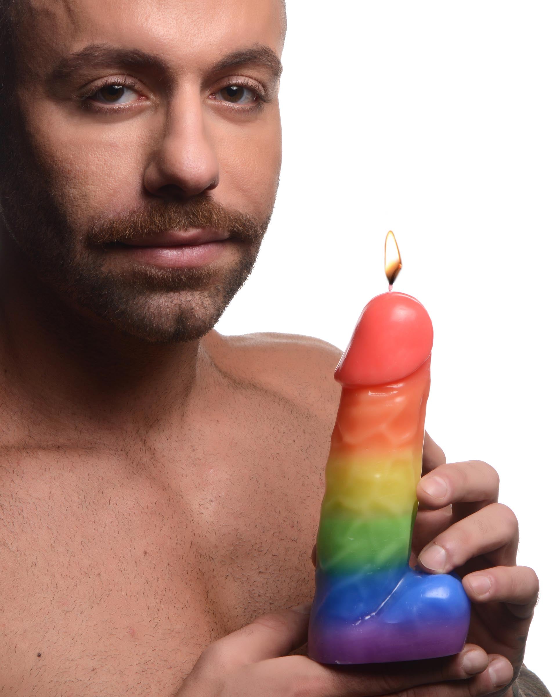 Man presenting the Pride Pecker Rainbow Candle without a shirt