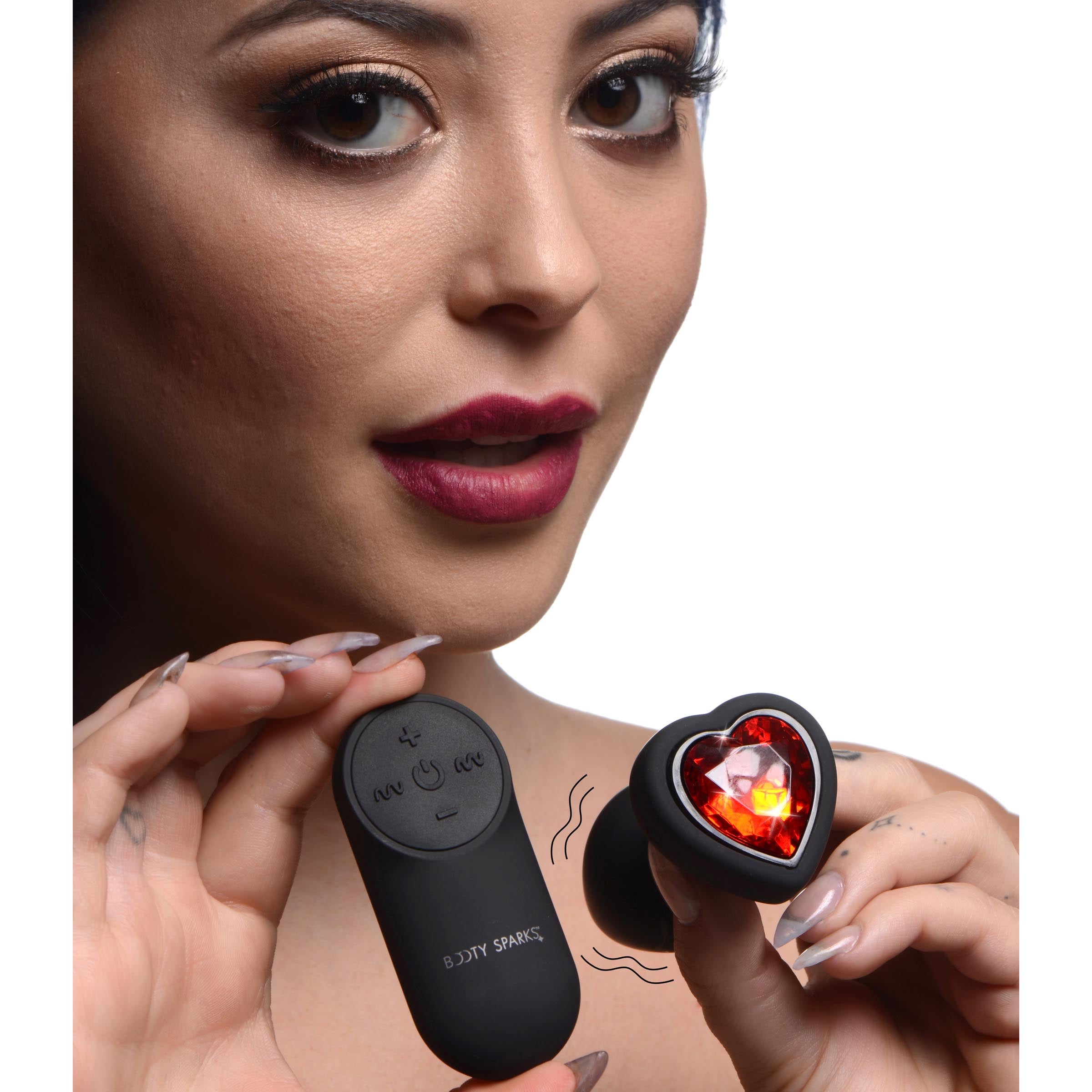 Hand holding a remote control for a vibrating anal plug with heart design