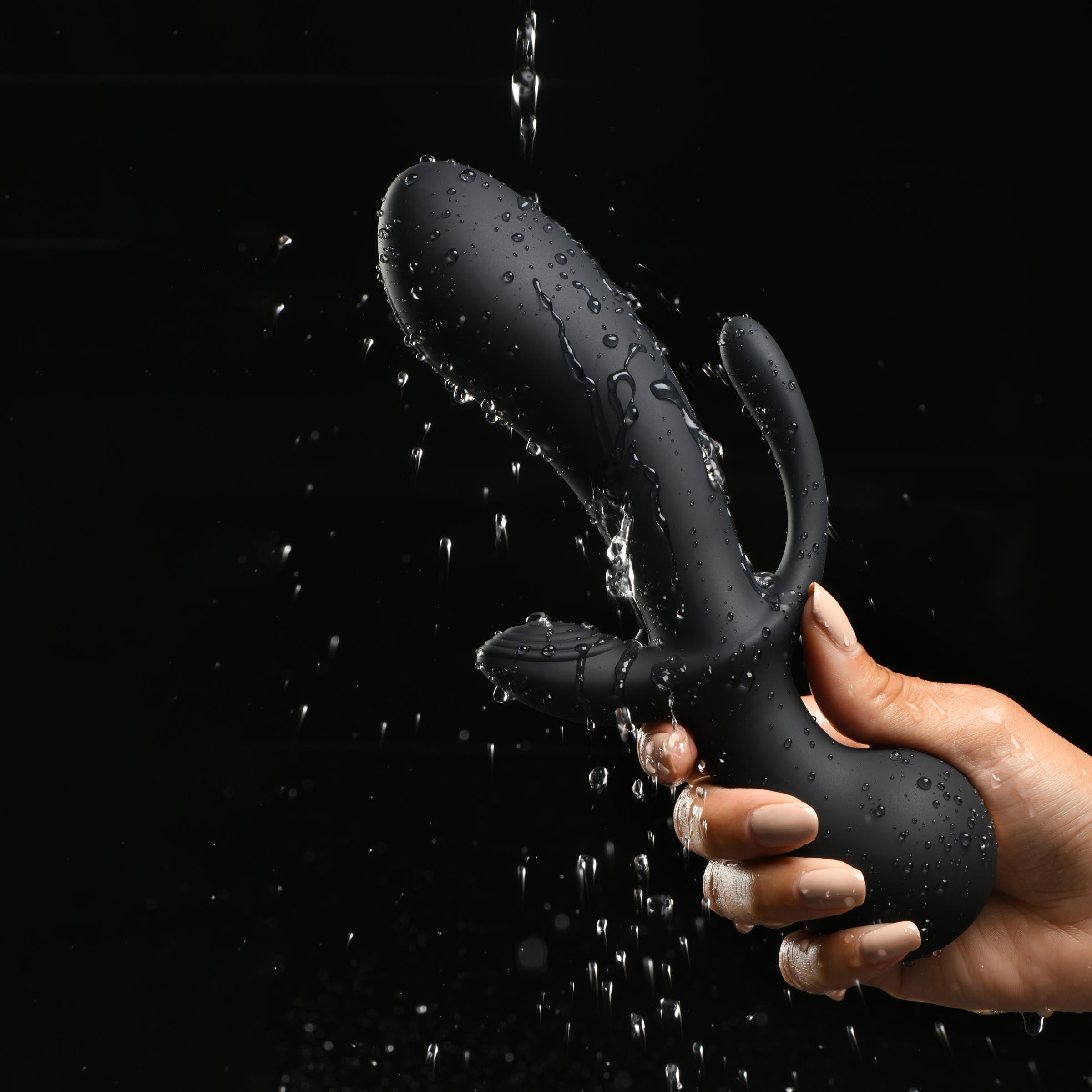 Person's hand displaying a silicone triple stimulator with visible water droplets