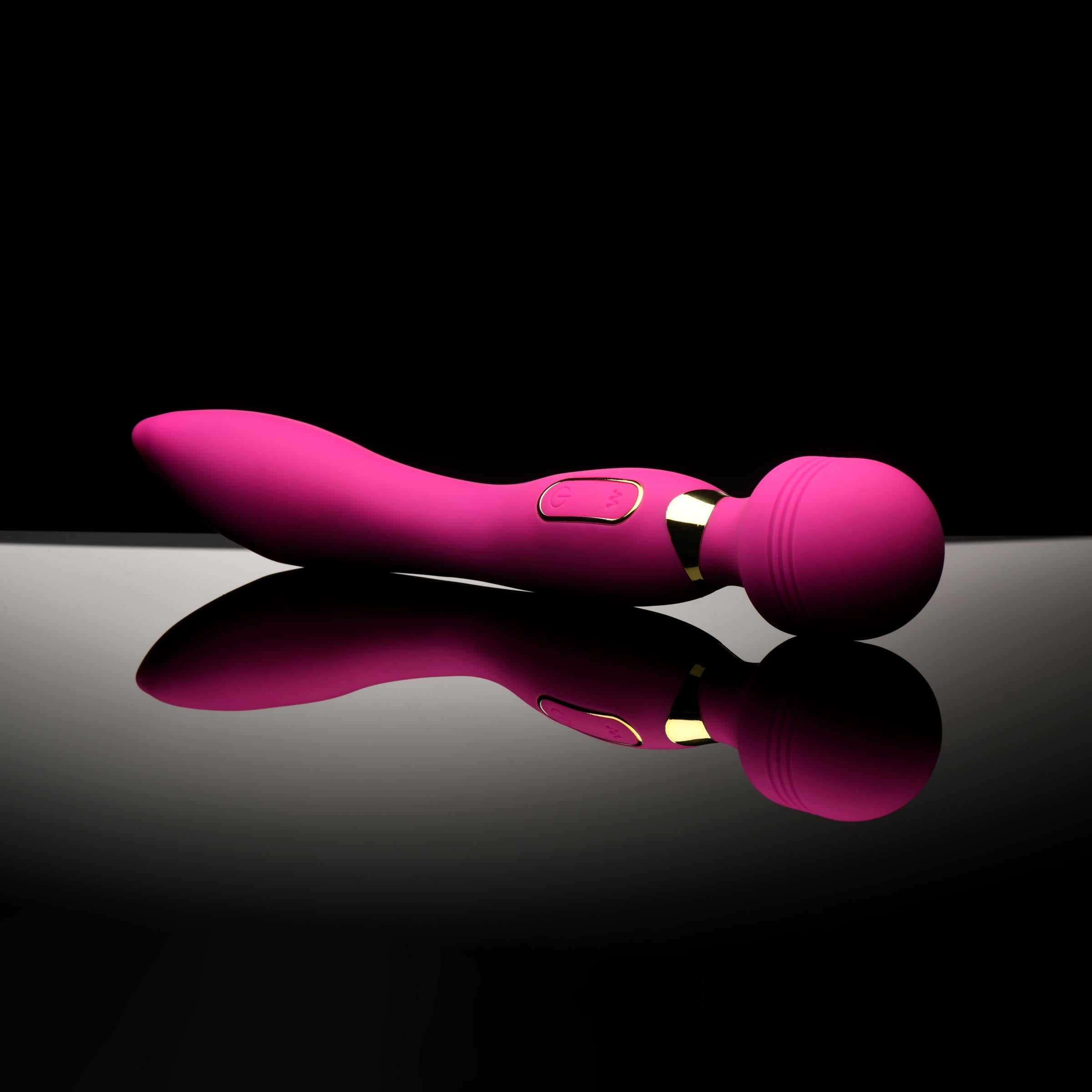 Pink silicone wand vibrator resting on a glossy surface