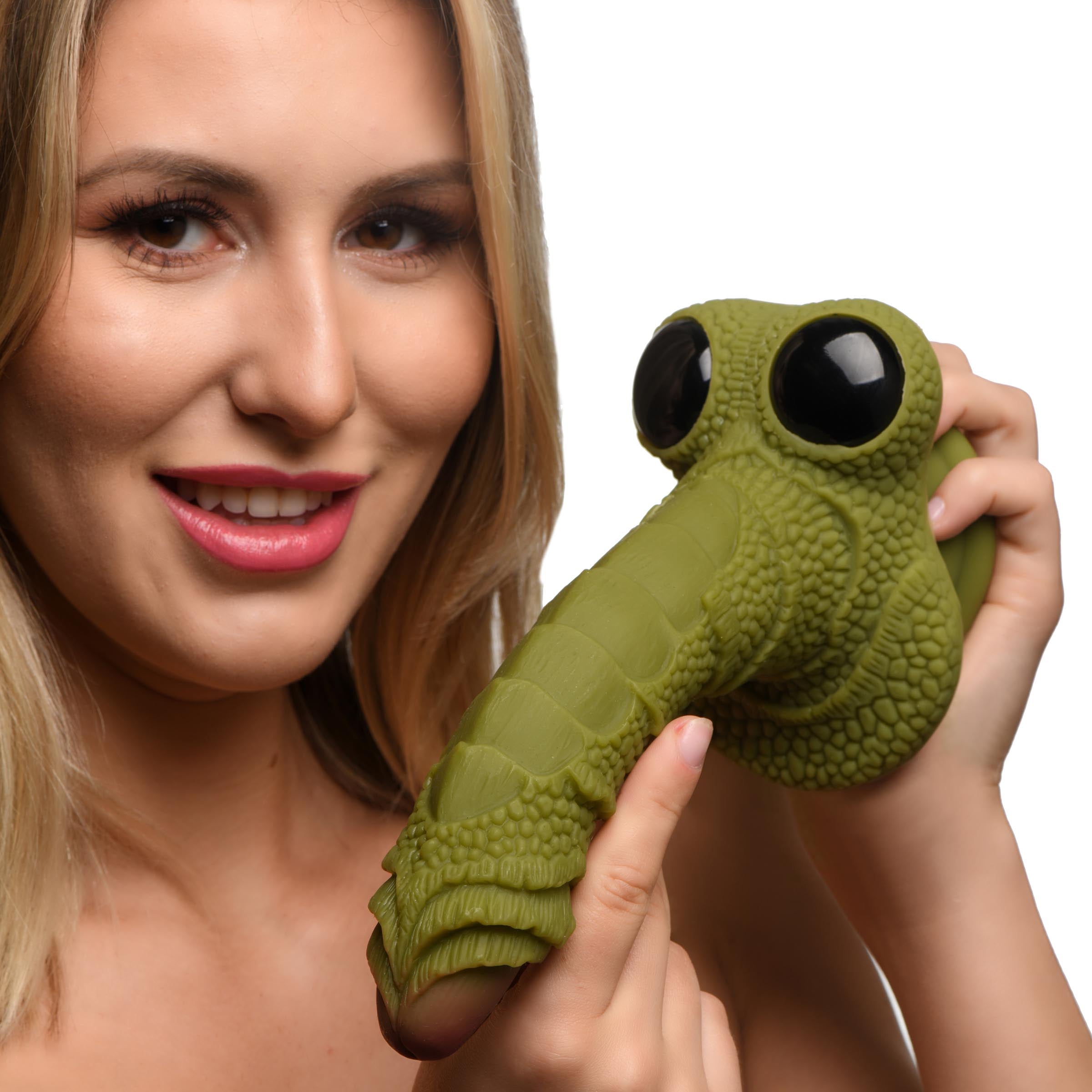 Close-up of a woman holding a green scaly silicone fantasy dildo