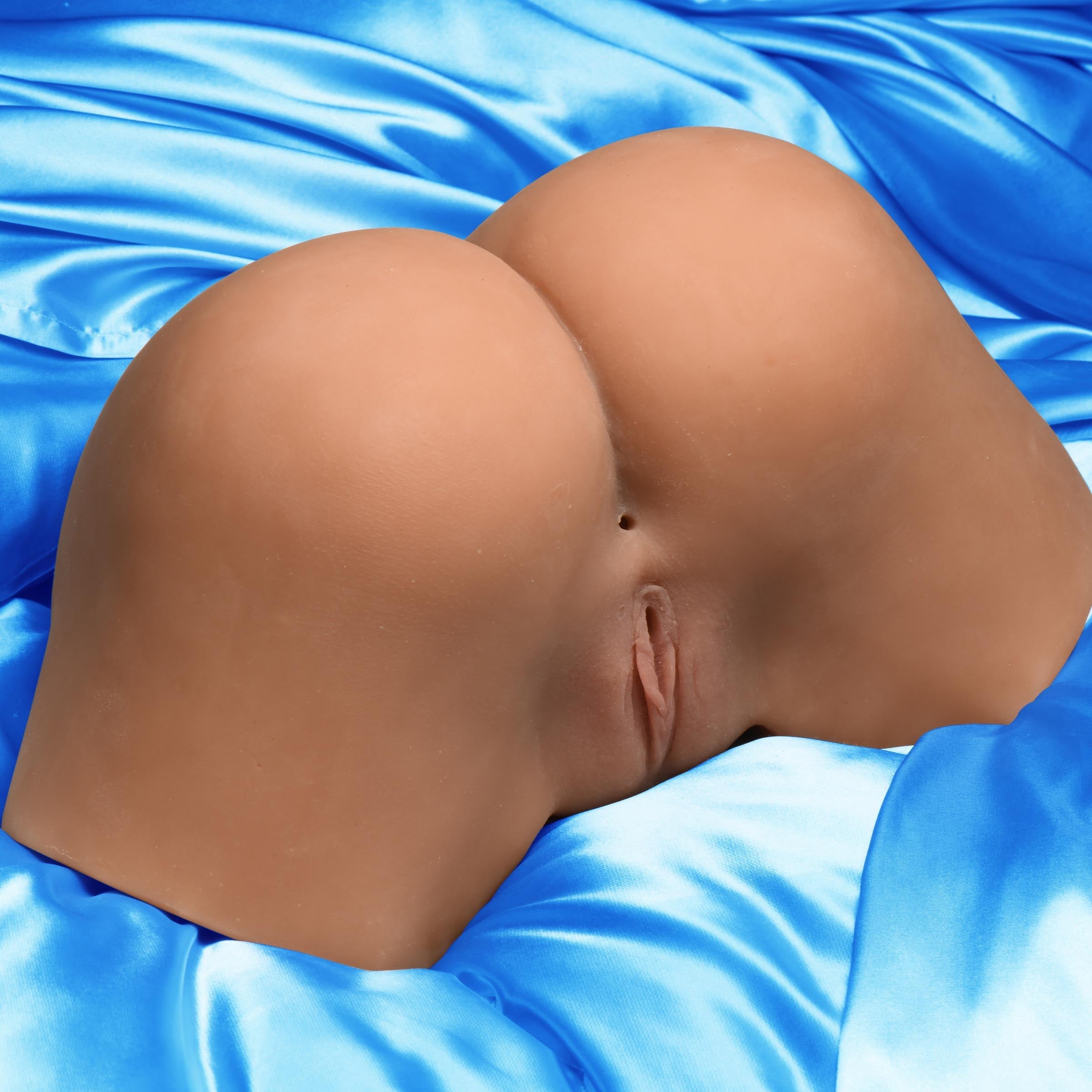 Detailed view of the masturbator toy's lifelike texture on a blue satin sheet