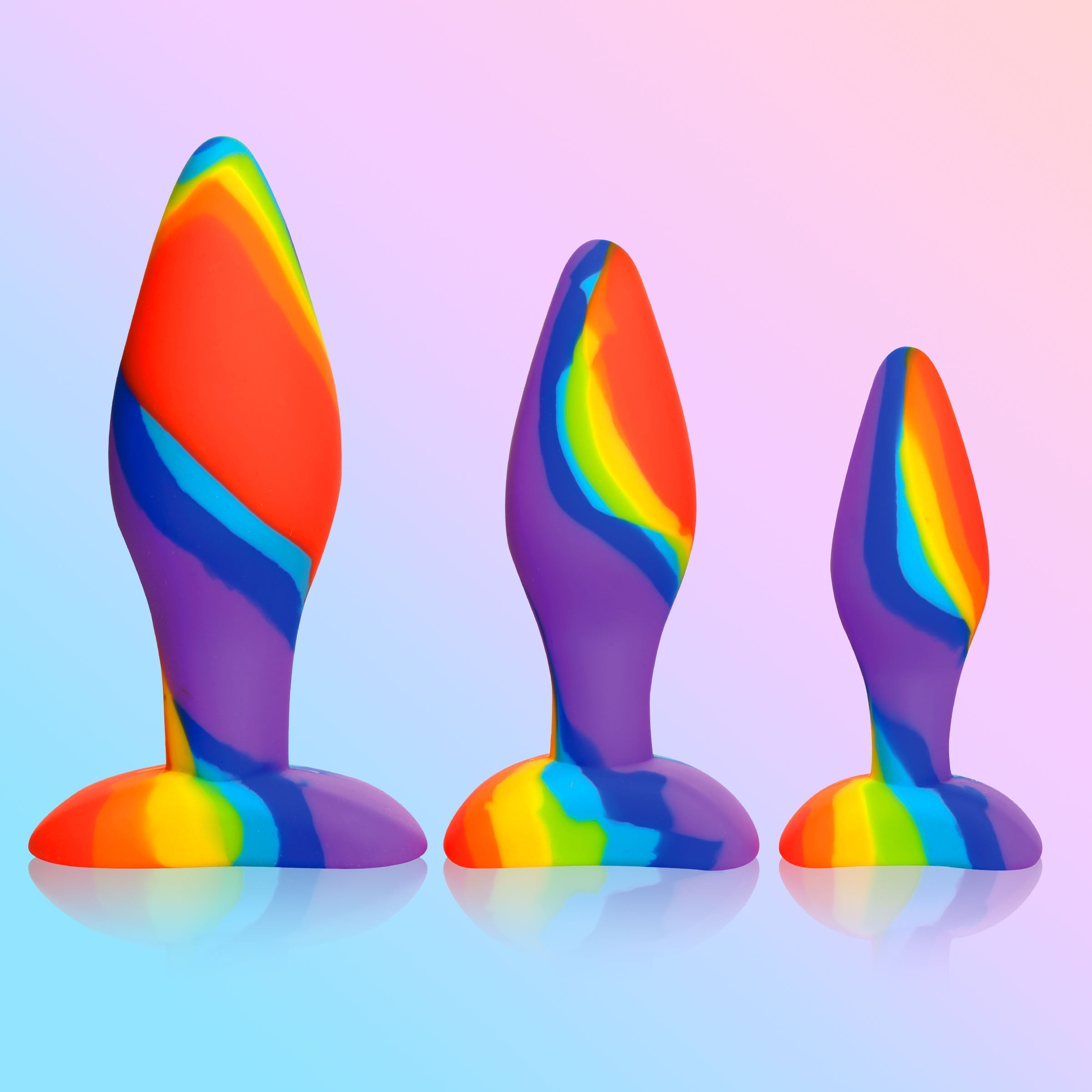 Trio of rainbow silicone butt plugs against a blue backdrop