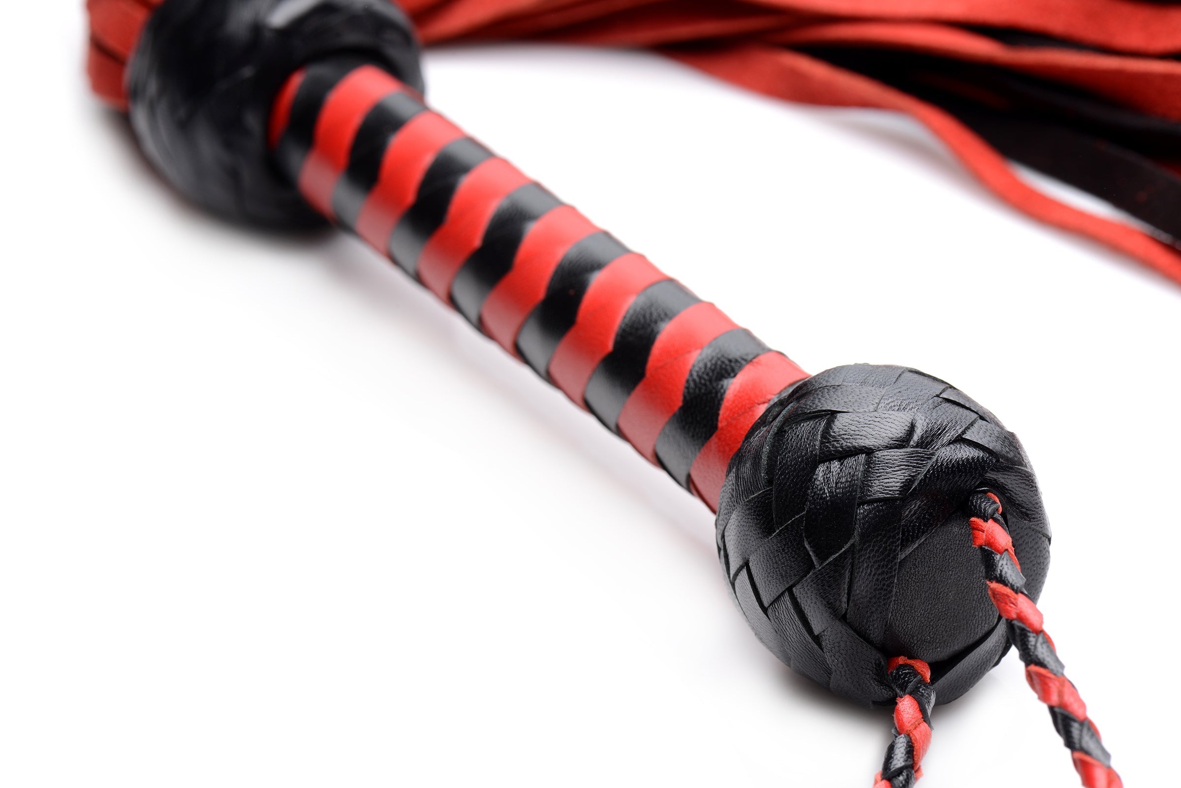 The Isabella Sinclaire suede flogger displayed with its red and black tails coiled